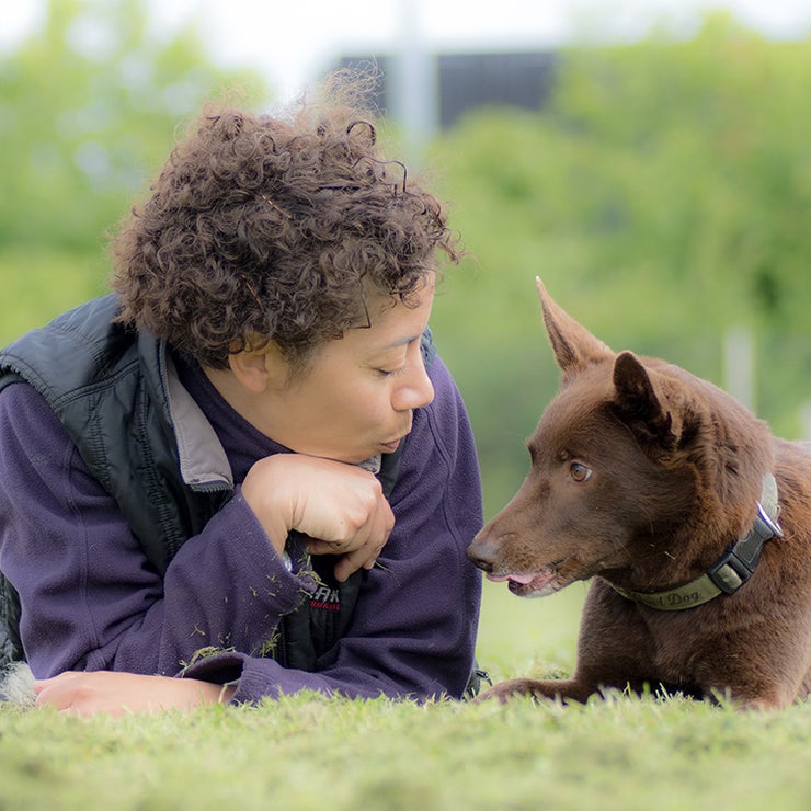Emelie Johnson Vegh lying on the grass face to face with a brown kelpie